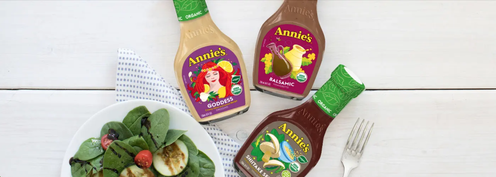 Three bottles of Annie’s Natural Salad Dressing next to a green salad